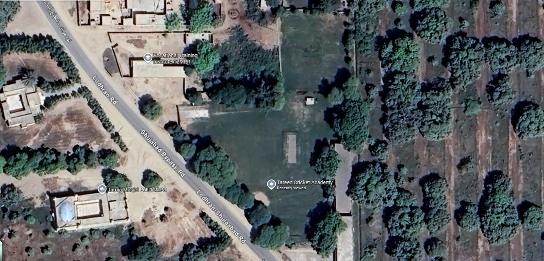 Aerial view of Tareen Cricket Academy in Lodhran, Pakistan, showcasing lush green pitches and training facilities surrounded by rural fields, with young players practicing under the guidance of coaches.